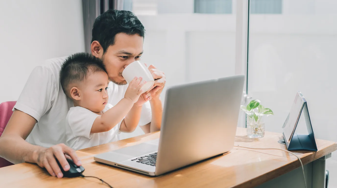 A dad working from home on mortgage research with his toddler on his lap