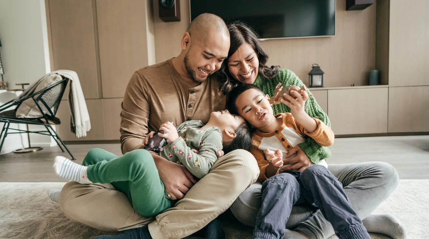 A family relaxing together on the living room floor of their home